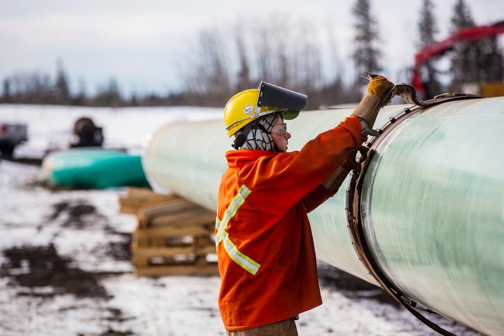 A Trans Mountain pipeline worker on site, next to the constructed pipeline.