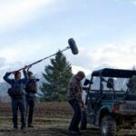 A man holding a mic boom over a filming scene from the documentary, "Tea Creek".