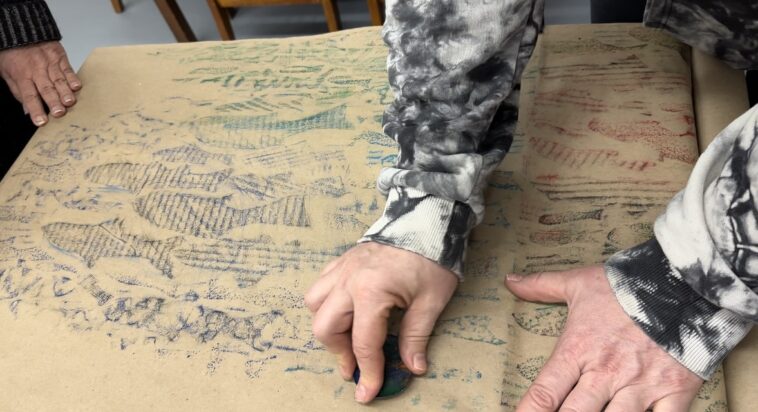 A person creating a fish rubbing