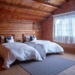 wooden cabin bedroom with two large beds next to a window