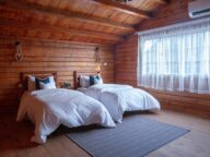 wooden cabin bedroom with two large beds next to a window