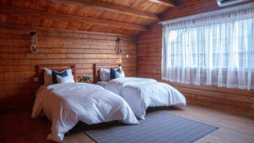 wooden cabin bedroom with two large beds next to a window