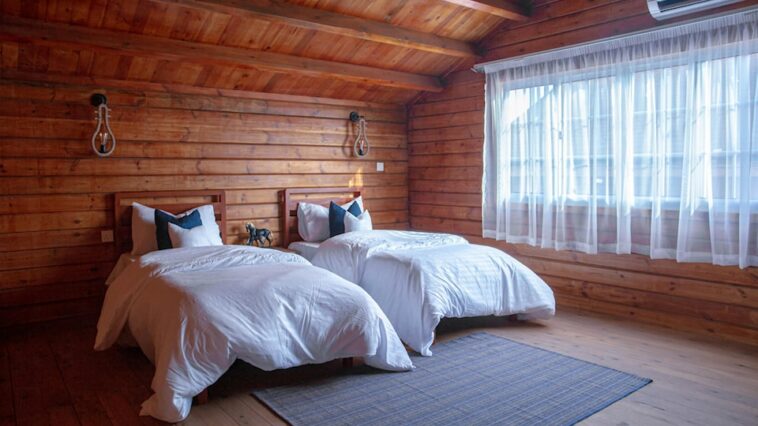 wooden cabin bedroom with two large beds next to a window