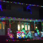 Neighborhood house at night lit up with christmas lights, minion inflatables snowmen and christmas decorations