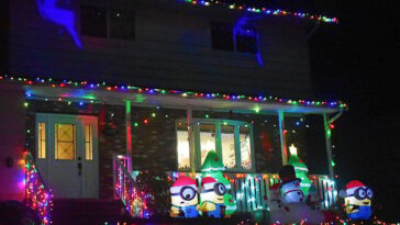 Neighborhood house at night lit up with christmas lights, minion inflatables snowmen and christmas decorations